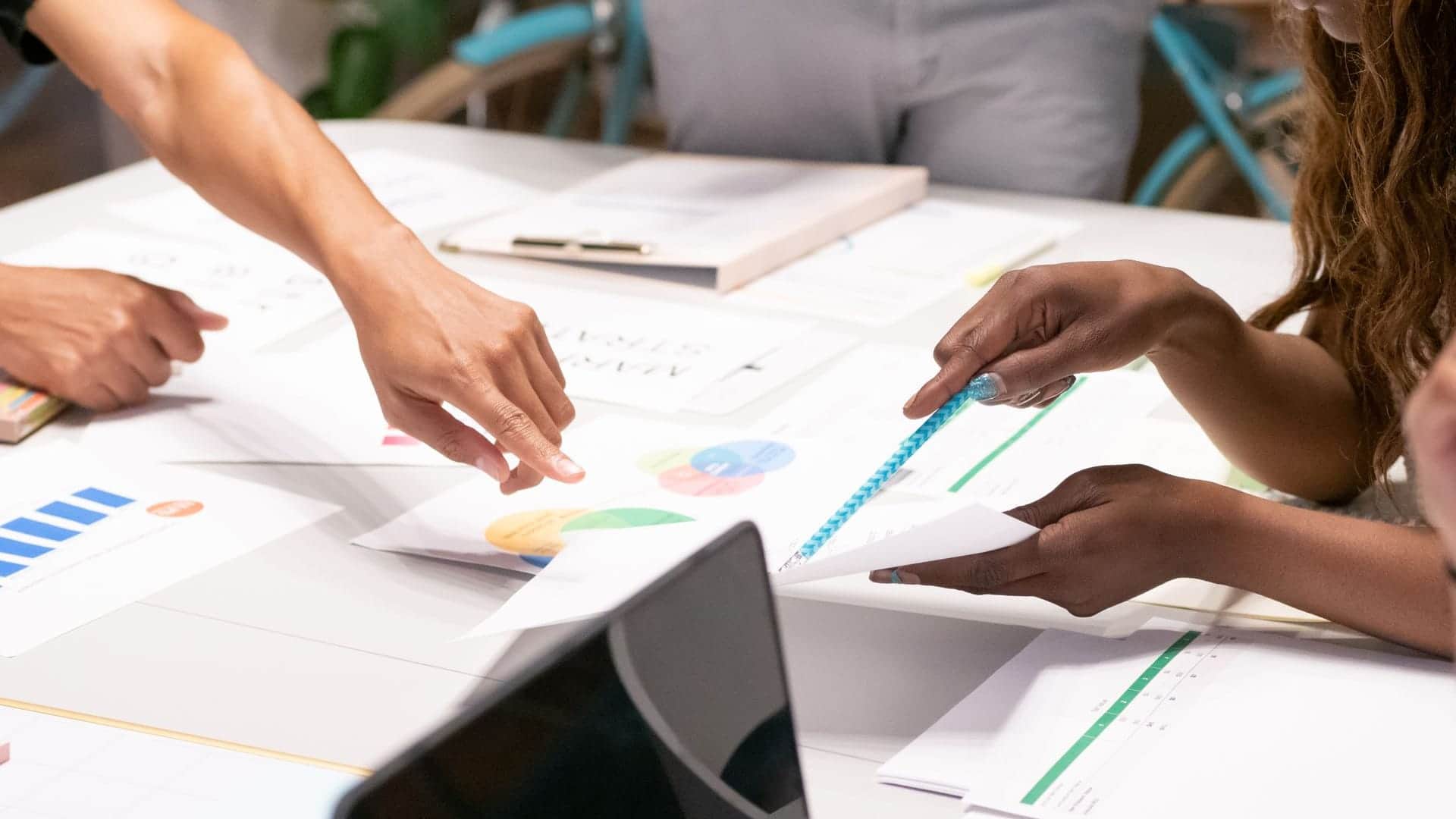 Equipo de trabajo revisando gráficas y documentos de estrategia digital sobre una mesa con un portátil