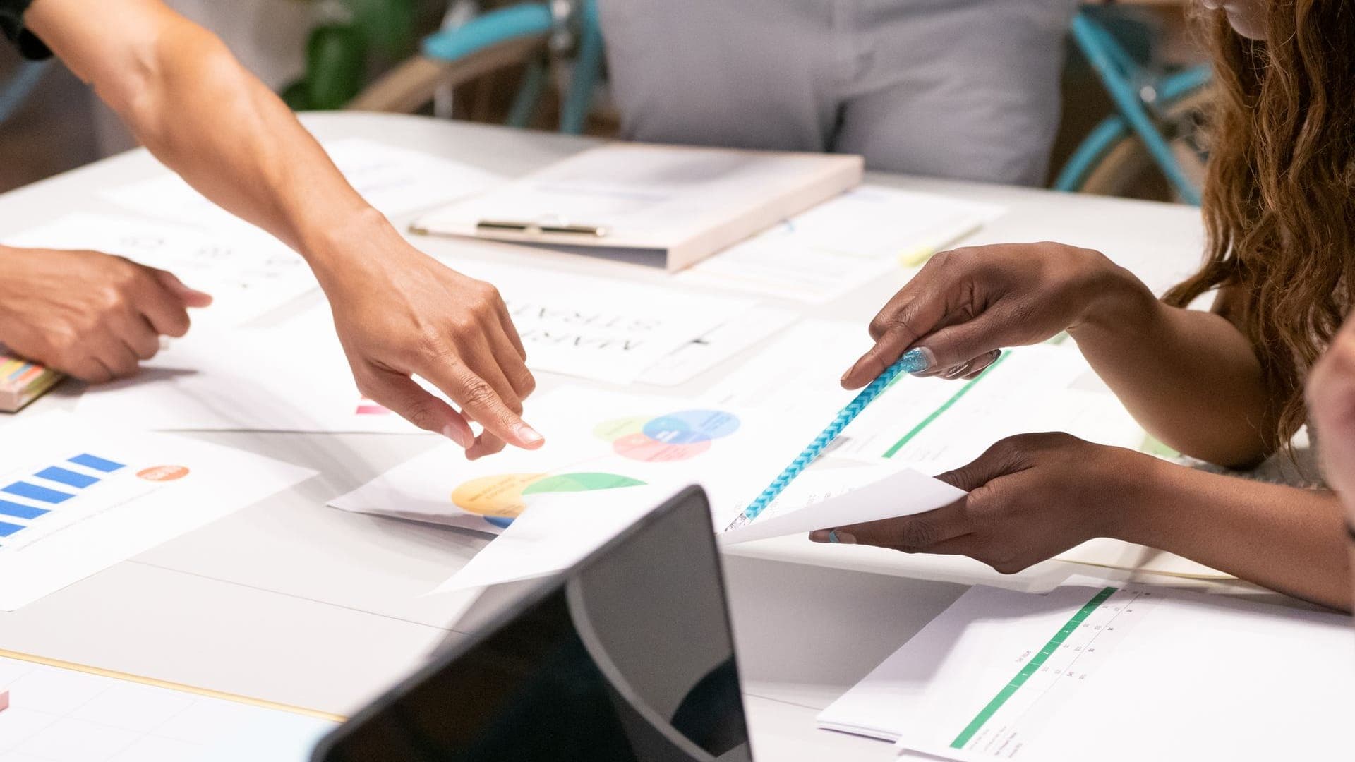 Equipo de trabajo revisando gráficas y documentos de estrategia digital sobre una mesa con un portátil